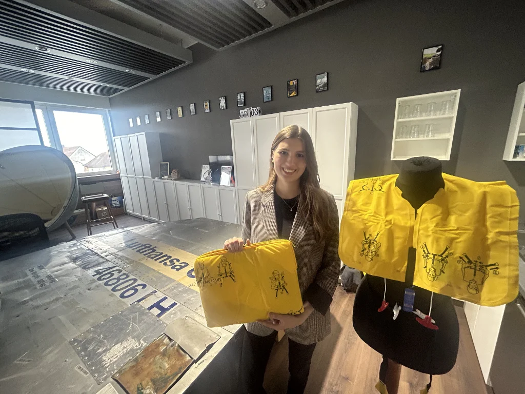 Marketingmanagerin Lucia Wachter zeigt eine ausrangierte Rettungsweste der Lufthansa und  eine der Laptoptaschen, die daraus entstanden sind